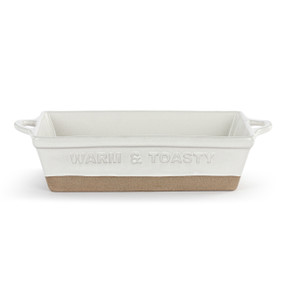 A white ceramic loaf dish with handles on the short ends and a tan textured base. The front of the loaf pan says "Warm & Toasty".