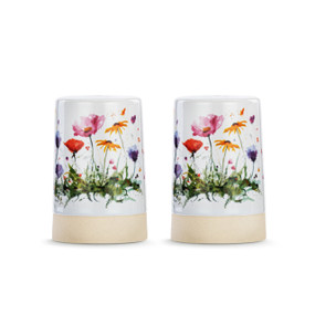 A set of two white ceramic salt and pepper shakers with a cream textured base. There is a watercolor image of wildflowers on them.