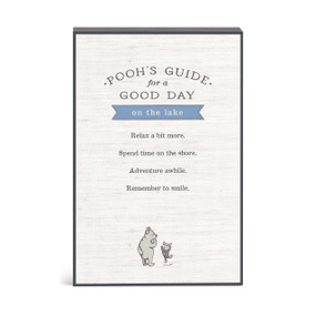 A wall art with an illustration of Pooh and Piglet with a message about Pooh's guide for a good day on the lake.