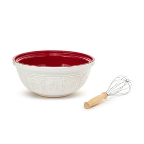 A white textured ceramic mixing bowl with a red interior and a whisk to the side.