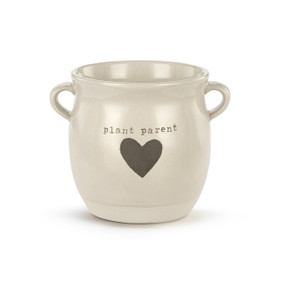A cream ceramic planter with two small handles on the sides. The planter says "plant parent" and has a gray heart on the front.