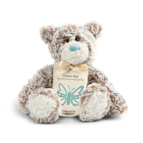 A gray and brown plush bear with a teal nose and a cream tag tied around its neck that says "Dream Big! Spread your wings and fly".