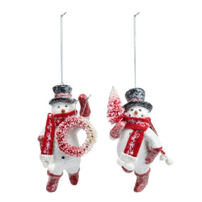 A set of two different snowman ornaments. Each is wearing red boots, scarf and a black top hat while holding either a wreath or small red tree.