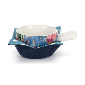 A white ceramic soup crock with a pink and blue hydrangea pattern nestled in a dark blue fabric cozy with a blue and white polka dot interior.