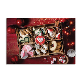 A 500 piece puzzle with an image of a box filled with different types of Christmas cookies and candy on a red wood table.