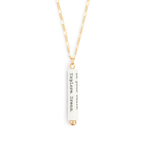 A gold chain necklace with a white scroll charm. The scroll has a saying from Mark Twain.