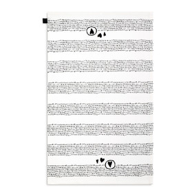 A white kitchen towel with illustrations of black dots and hearts displayed with the towel laid out flat.