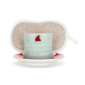 A light green ceramic soap dish with the saying "All I Want For Christmas Is A Clean House" and a Santa hat on the front, with a tan sponge in the open slot.