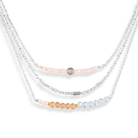 A layered silver necklace made of three different chains with blue and brown beads on them.