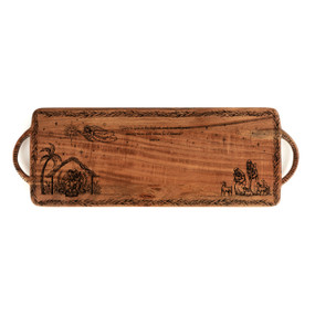 A dark wood rectangular serving board with engravings of the nativity scene and scripture.