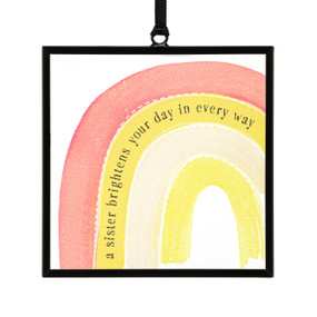A small square shaped sun catcher with an illustrated yellow and red rainbow and the saying "a sister brightens your day in every way".