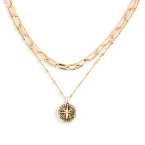 Detail view of the charm on a gold chain adjustable necklace with a round gold pendant in a compass shape that says "Protect Us Guide Us".