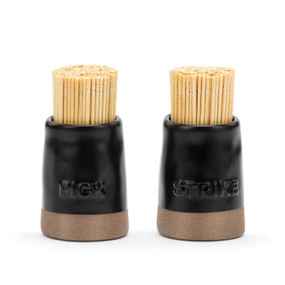 A set of two black ceramic toothpick and match holders with a brown textured base. One says "Pick" and the other says "Strike", displayed with toothpicks in them.