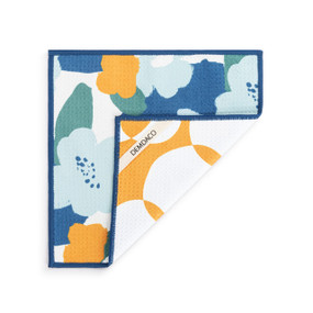 A double sided square dish cloth that is white on one side with large blue floral illustrations, displayed with a corner turned back.