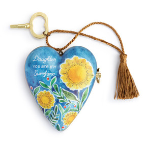A heart shaped musical sculpture in a blue and yellow floral pattern that reads "Daughter You are my Sunshine". The heart has a bronze tassel and gold key attached.