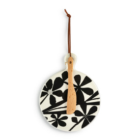 A round ceramic mini serving board with a bold black and white floral pattern. The board has a small wood knife attached.
