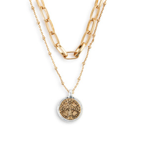 Detail view of the medallion on a double gold chain necklace with an adjustable clasp and a round cross medallion with a silver rim.