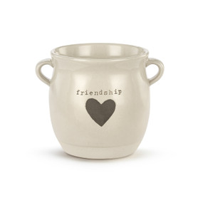 A cream ceramic planter with two small handles on the sides. The planter says "friendship" and has a gray heart on the front.