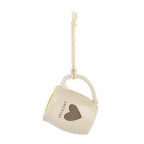 A cream ceramic mini mug that says "teacher" with the image of a heart on the front, shown hanging with a coffee pod inside.
