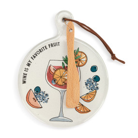 A round ceramic white mini serving board with an illustration of a wine glass and the saying "Wine Is My Favorite Fruit". The board has a small wood knife attached.