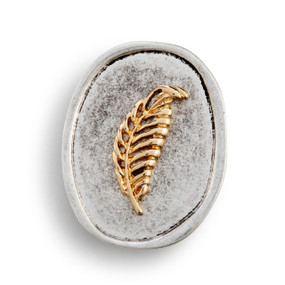 An oval silver metal token with a gold metal feather on it.