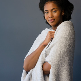 A woman wearing a smoke colored wrap against a blue gray background.