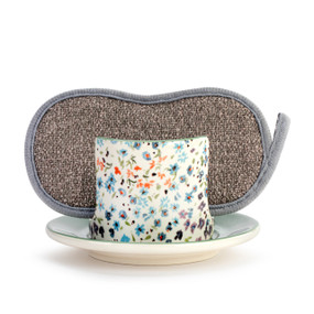 A white ceramic soap dish that has small colorful flowers on it, with a gray sponge in the open slot.