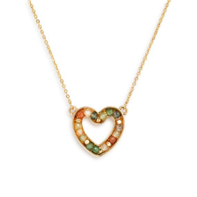 Detail view of the charm on a gold chain necklace with a heart shaped charm filled with small green stones.