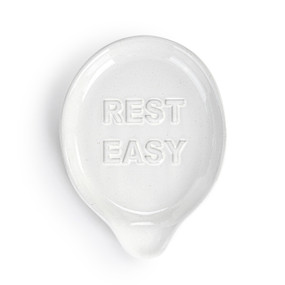 A white ceramic spoon rest that says "Rest Easy".