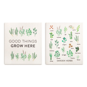 Two biodegradable dish cloths, one has herb illustrations and the saying "Good Things Grow Here" and the other has illustrations of different garden herbs.