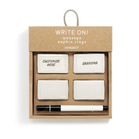 A set of four white ceramic napkin rings that come with a black write on pen to personalize them, displayed in a packaging box.