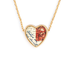 Detail view of the charm on an adjustable gold chain necklace with a heart shaped charm of a red and white postal stamp.