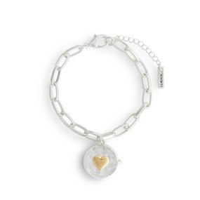 A silver chain bracelet with a lobster clasp and a round silver locket charm that has a gold heart on the front.