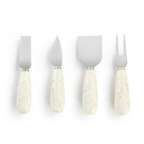 A set of four serving utensils with cream handles that have a leaf pattern.