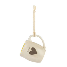 A cream ceramic mini mug that says "nurse" with the image of a heart on the front, shown hanging with a coffee pod inside.