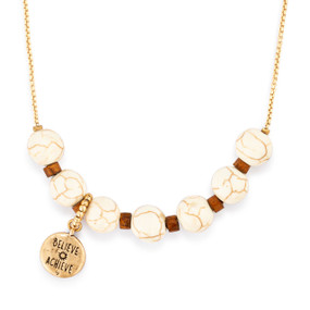 An adjustable gold chain necklace with seven gold and ivory beads spaced on it with a charm saying "Believe Achieve" that can move across the beads to track habits.