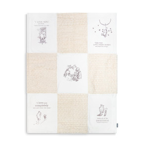 A cream and white nine patch blanket with illustrations from Winnie-the-Pooh in five of the squares.