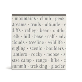 A white square wall art with words about the mountains on it.