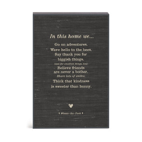 A black Winnie-the-Pooh inspired wall art with a message about what they do "In this home..."