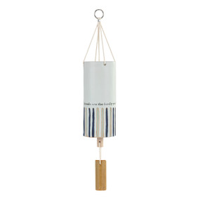 A white tubular ceramic wind chime with a wood chime and tan and blue vertical stripes on the bottom half. The chime says "Friends are the family you find along the way".