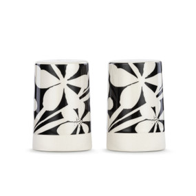 A set of two white ceramic salt and pepper shakers with a cream textured base. There is an image of bold black and white florals on them.
