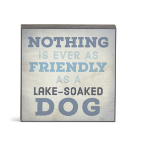 A small square gray wall art with the saying "Nothing is ever as friendly as a lake-soaked dog".