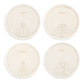 Four different cream ceramic appetizer plates each with a different nativity scene and word.