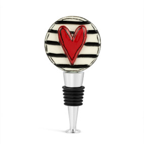A silver and black bottle stopper with a white and black striped ceramic circle on top with a raised red heart.