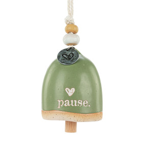 A mini green bell with a cream heart and the word "pause". There are beads and a metal token at the top of the bell.