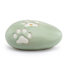 A green stoneware rock with two white paw prints, one with a gold heart in the center.