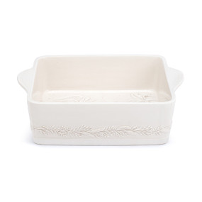 A square cream ceramic baking dish with a pattern of branches around the outside.