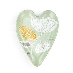 A light green heart shaped ceramic spoon rest with a floral illustration on it.