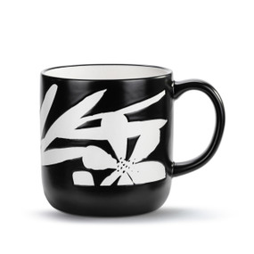A black ceramic mug with a bold white floral pattern.