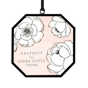 A small octagon shaped sun catcher with illustrated white flowers, a peach background and the saying "Grateful for Every Little Thing".